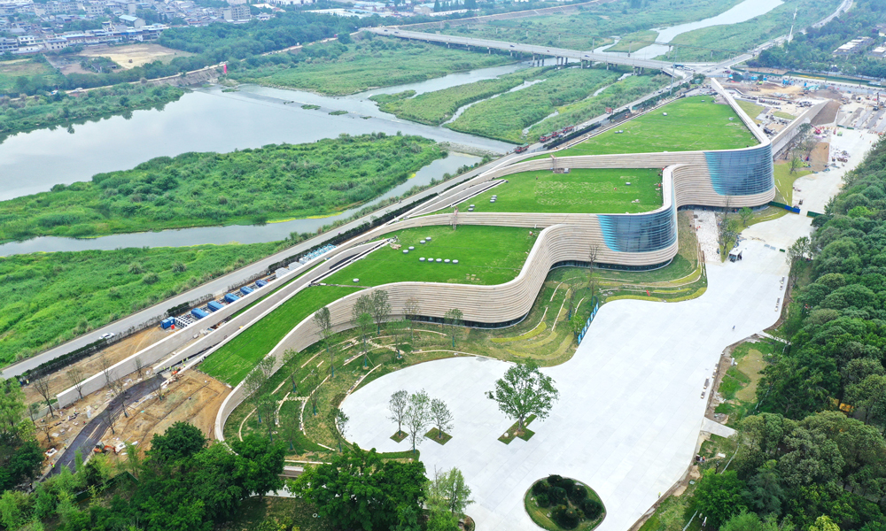 三星堆博物馆新馆屋顶选用了固化纤维土全种植屋面，绿植种植面积约2.7万平方米。从空中俯瞰，整个新馆与大地融为一体，实现了建筑消隐融于环境的设计初衷。考虑到斜屋面绿化种植特点，建设团队在建设过程中将植物纤维、有机化合物和营养物质通过微波加热及机械压缩形成固化土基质，用于屋面种植。这种基质土层饱水荷载小于45公斤每平方米，可以有效降低屋面覆土荷载，实现了建筑材料从原材料、生产到使用全过程的低碳化，也降低了斜屋面绿植运营养护土壤的营养流失。建设期间，项目还通过太阳能、风能利用，噪音控制、扬尘控制等系统，实现了全过程绿色建造。