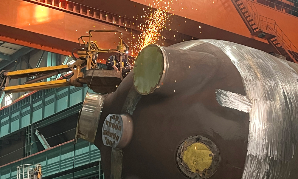 哈电集团重装公司廉江项目生产现场，磨锉工在进行吊耳隔离层打磨的工作。