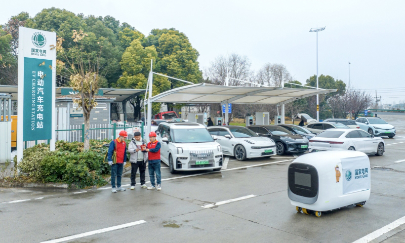 国家电网安徽马鞍山供电公司工作人员在高速公路充电站指导客户操作充电机器人。