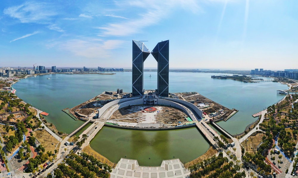 近日，位于中国（上海）自由贸易试验区临港新片区，由中国建筑旗下中建二局华东公司承建的临港西岛中银金融中心项目建设取得新进展，项目外立面幕墙施工进入收尾阶段，滴水湖畔“双子塔”，临港第一高地标雄姿初现。图为空中俯瞰位于临港新片区滴水湖畔的中银金融中心大楼。