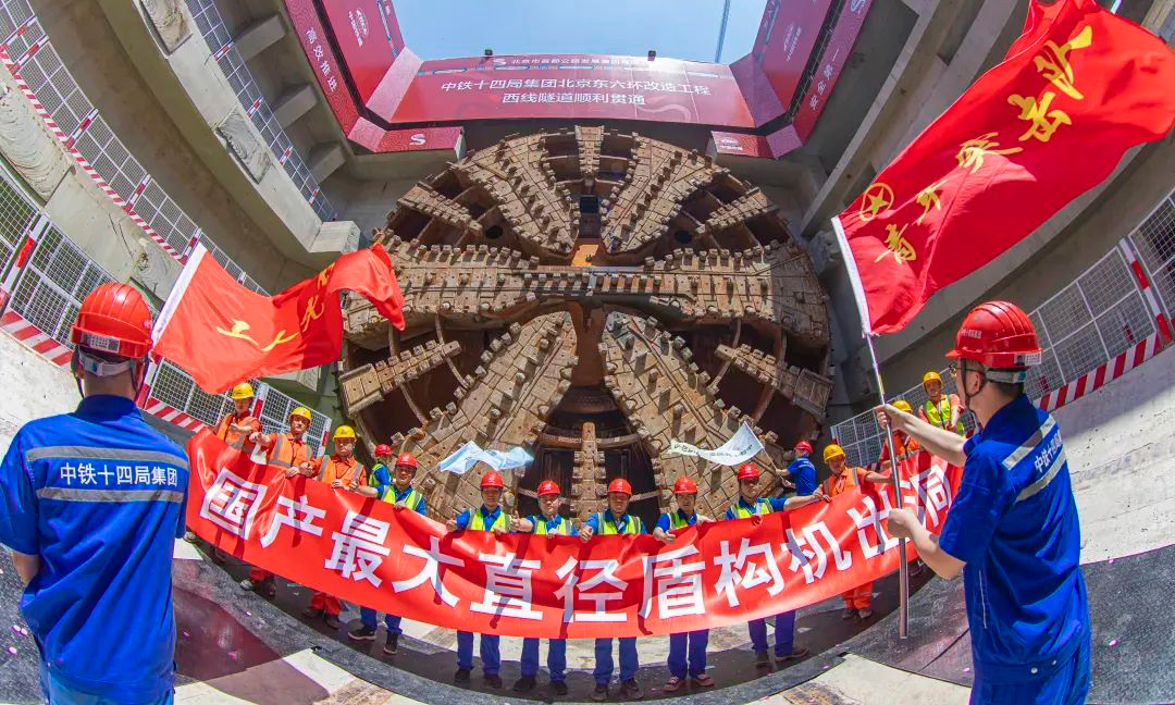 针对施工难点，项目团队量身定制了“京华号”盾构机，这是当时国产最大直径盾构机，也是国产首台16米级超大直径盾构机。自建设以来，“京华号”先后攻克高风险吊装、浅覆土始发、长距离穿越高致密砂层等11项技术难题，历经24个月的施工，完成7.4公里西线隧道掘进任务，并创造了单月进尺542米的掘进纪录，申报研发工法、专利等23项。图为“京华号”盾构机出洞。