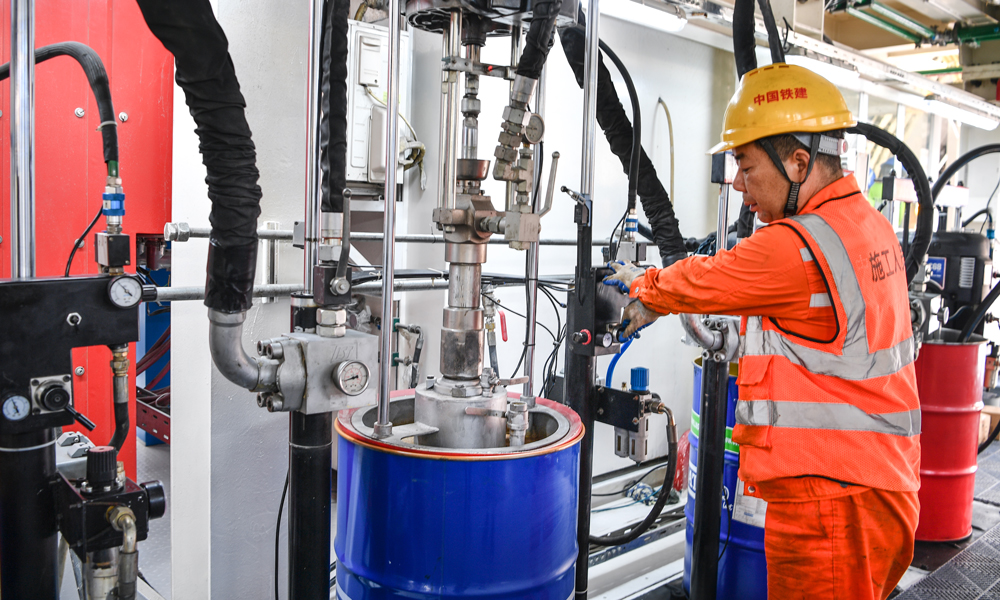 针对隧道施工风险和难点，项目团队加强技术攻关，对“厦金号”盾构机进行针对性设计，配备了带压复合型刀盘，配置144把滚刀，增加刀具强度和旋转轨迹，使刀盘整体切削性能和破岩效率得到显著提升，还搭载了伸缩主驱动、同步双液注浆、刀盘刀具磨损自动监测、盾尾间隙自动测量、管片上浮自动测量、硬岩二次破碎等先进智能掘进和监测装置，同时运用“智慧指挥中心”实现施工现场实时安全和信息化管控，确保隧道安全高效掘进。图为施工人员检查油脂情况。 