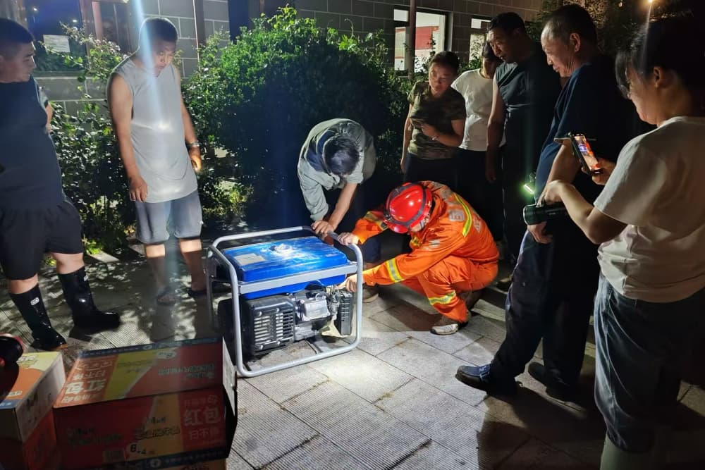 7月27日22时，国网北京电力综合应急救援队队员付佳文为密云河北村村委会送去两台发电机作为应急电源，并为村民讲解使用方法。