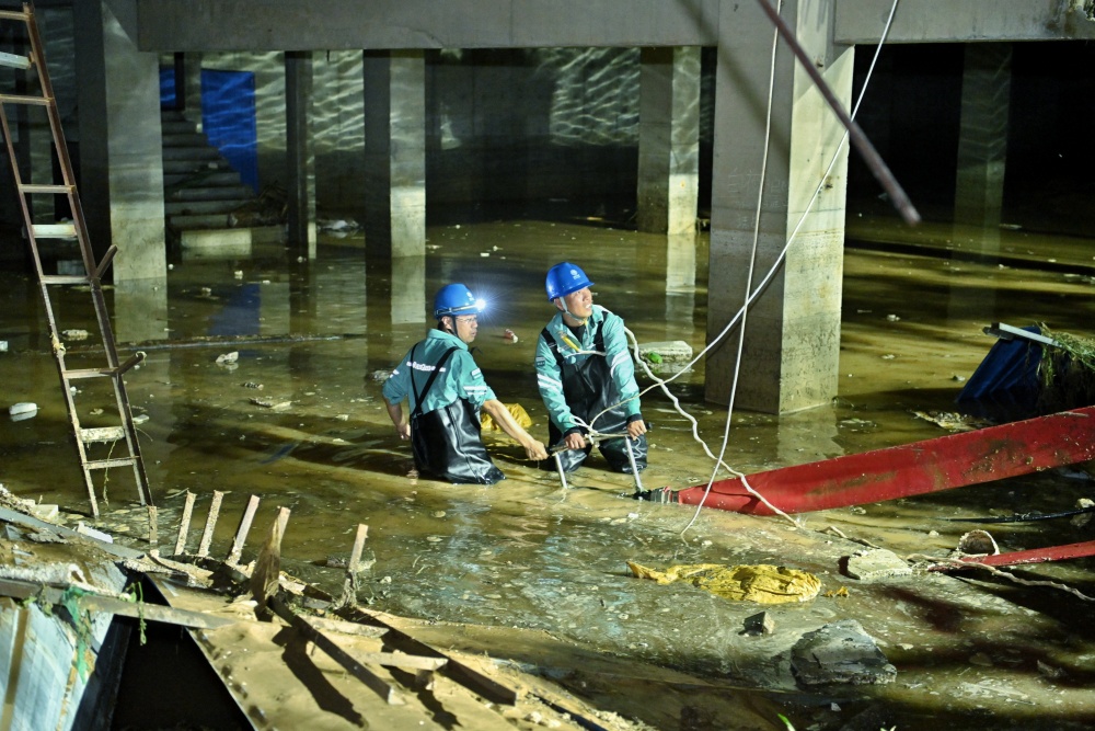 7月26日，国网河北衡水供电公司支援队员在保定阜平县假日兰庭小区抽排地下配电室附近积水。