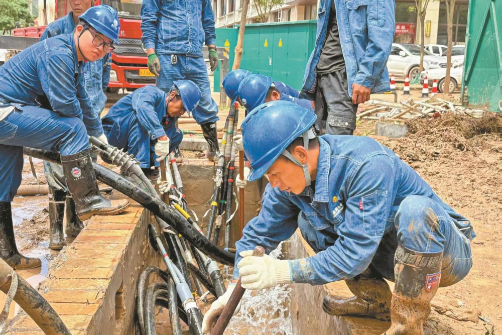 7月26日，陕西延安吴起供电公司抢修员工石磊、李治林等在吴起县长征街清理10千伏县城三线12号环网柜电缆沟的淤泥和积水。