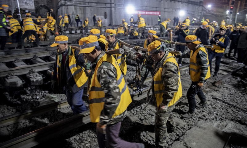 图为1月15日凌晨，中铁十一局施工人员在西安站改扩建工程现场抬运钢轨。（新华社记者 陶明 摄）