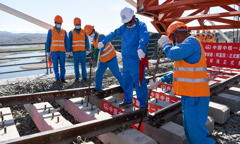 阿富准铁路预计于今年8月30日开通运营，届时北疆环线将提高北疆铁路运输效能，推动地区经济发展。图为7月2日，中铁一局的施工人员在阿富准铁路阿勒泰至富蕴段进行铺轨作业。（新华社记者 丁磊 摄）