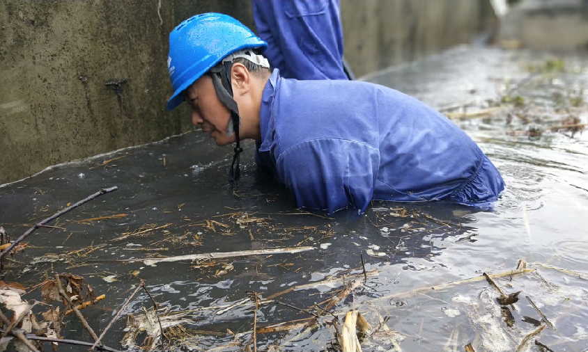 国家能源集团荆门发电公司防汛突击队队员清理排泄口杂物。