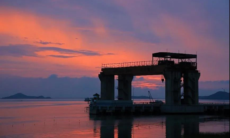 工业发展催生了建筑工业的繁荣。夕阳下，重件码头与晚霞、滩涂融为一体。