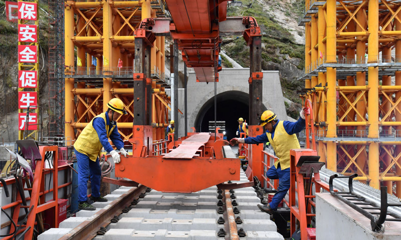 拉萨至林芝铁路是国家“十三五”规划重点工程项目，全长435公里，设计时速160公里，是西藏首条电气化铁路，全线16次跨越雅鲁藏布江，地质条件复杂，桥隧比高达75%。图为9月20日，中铁十一局工程技术人员在藏木特大桥上铺轨。（新华社记者 觉果 摄）