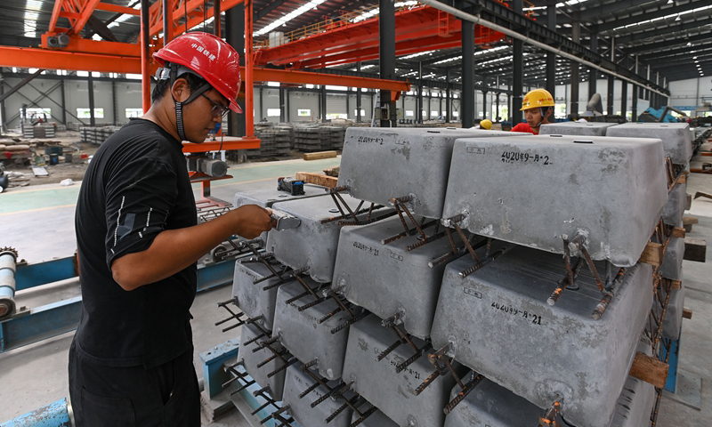 图为9月22日，工人在中国铁建华南建设有限公司南沙混凝土制品加工中心地铁轨枕生产线上给混凝土轨枕印制生产日期。（新华社记者 刘大伟 摄）
