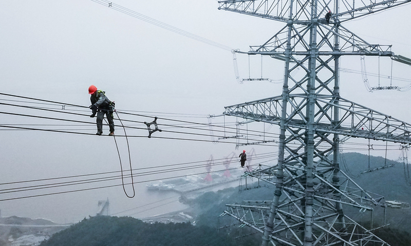 图为10月23日，检修人员在跨海输电高塔上进行走线工作。（新华社记者 徐昱 摄）