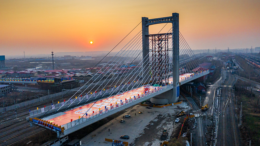 两座斜拉索主桥利用球铰转盘进行转体的总体方案，两座主塔转体总重量达到5.6万吨，是全世界高寒地区转体重量最大的斜拉桥。同时，该桥两侧转体主梁长度差达17米，需在转体期间进行1200吨的配重保持转体稳定性，这是中国国内采用不平衡转体法设计施工的最重桥梁，转体施工也是世界高寒地区城市立交桥上跨大型铁路编组站首例。图为正在缓缓转动的哈西大桥主塔和连续梁。