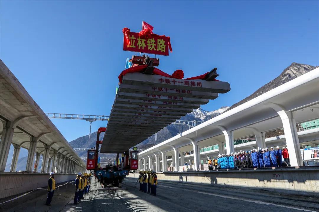 2020年12月31日，在西藏林芝市川藏铁路拉萨至林芝段（拉林铁路）铺轨现场，随着作业人员将最后一排长25米的轨排缓缓的铺设在林芝站正线路基上，标志着拉林铁路全线轨道铺通，为铁路后续建成通车打下坚实基础。图为最后一排轨排铺设现场。