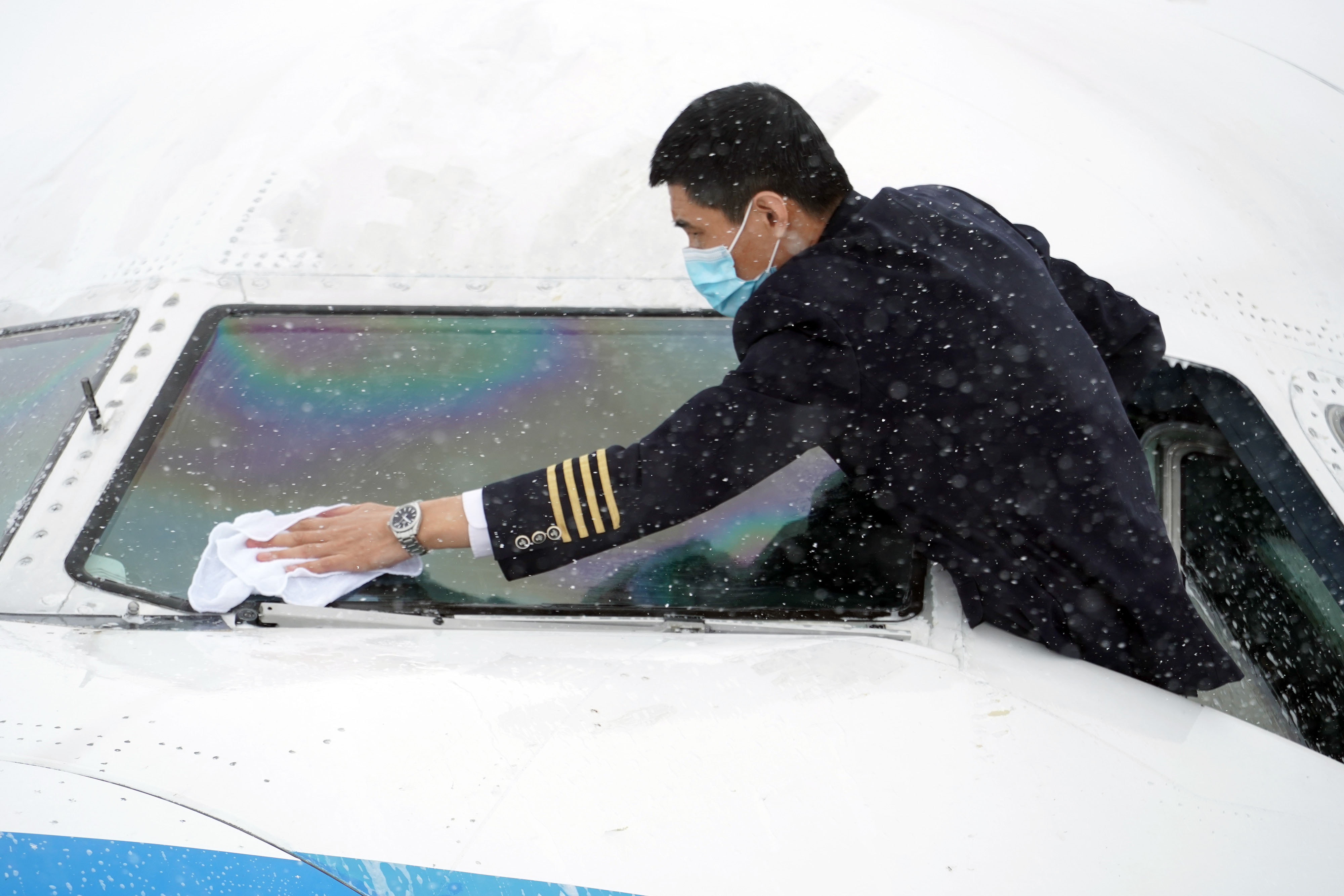 南航飞行人员清理飞机风挡积雪，为飞行做好准备。