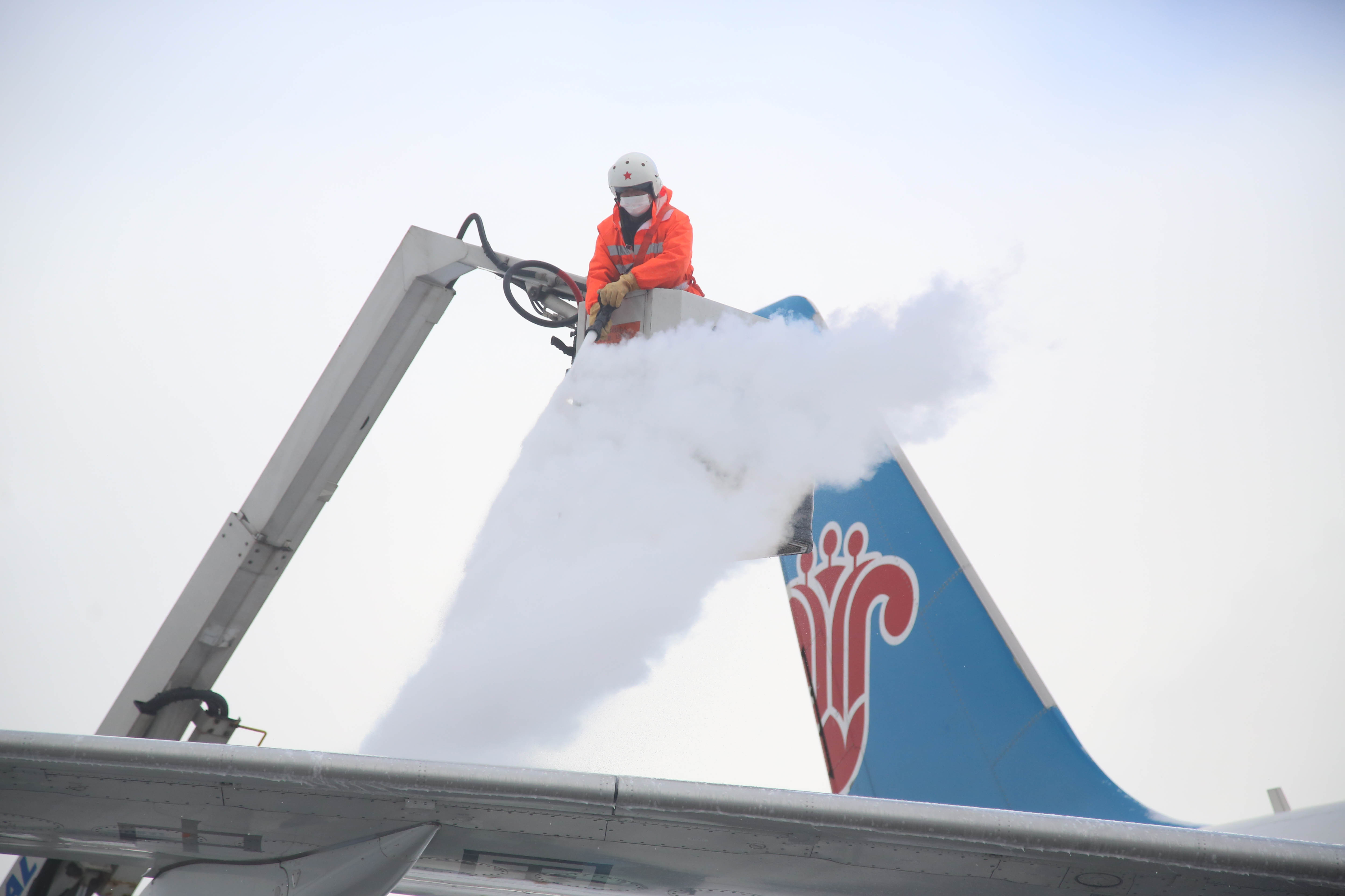 工作人员使用专业设备清除机身积雪。