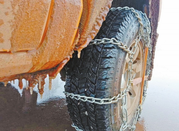 图为1月9日，新一轮寒潮袭击云南省泸西县，导致路边结冰，为确保行车安全，巡线人员对车辆加装防滑链。（子晓东 摄）