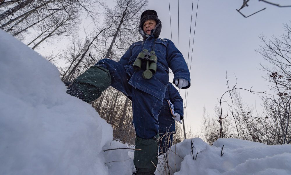 图为1月12日，吕建生（前）和王少亭在北极村附近的山林中进行电力巡线。（新华社记者 谢剑飞 摄）