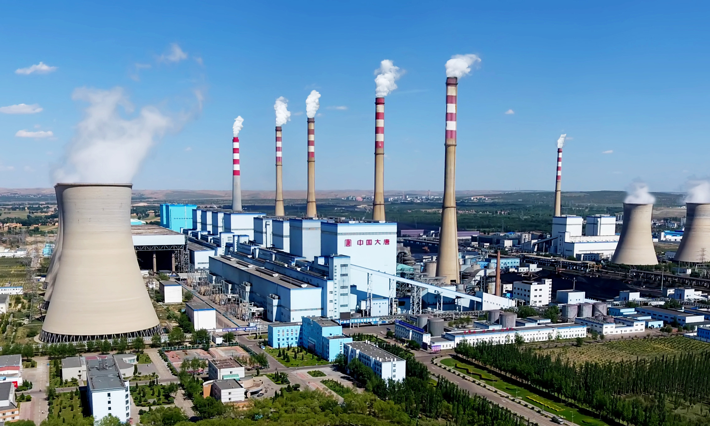 在距离内蒙古呼和浩特市以南70公里的地方，有一座名为托克托的县城，这里坐落着世界在役最大的火力发电厂——大唐国际托克托发电有限责任公司。托电公司是确保首都安全用电的主力电厂，年发电量约占北京地区社会用电总量的四分之一。作为火电领域的“巨无霸”企业，拥有12台机组、被称为“火电航母”的大唐托电总装机容量达到672万千瓦，肩负的节能减排责任巨大。图为大唐托电厂区。(供图：中国大唐集团公司)