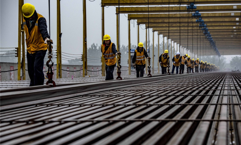 5月5日，中铁十一局职工在汉十高铁枣阳铺轨基地堆码500米长轨。（新华社记者 杜华举 摄）