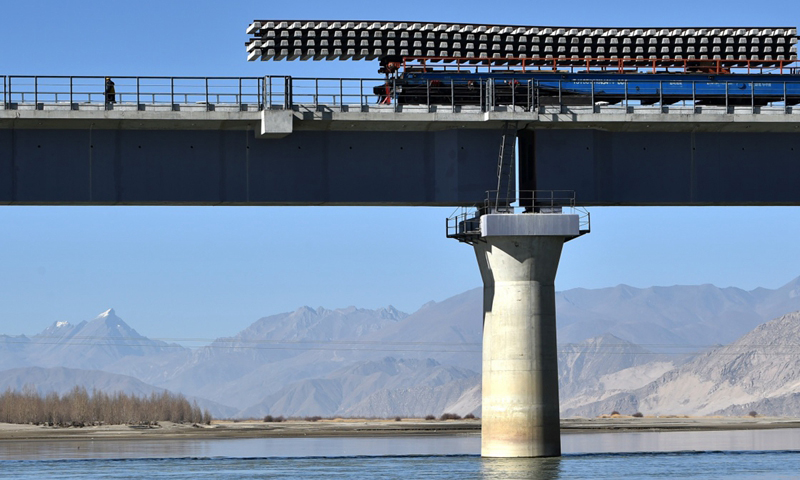 图为11月26日，中铁十一局施工人员在川藏铁路拉林段贡嘎雅鲁藏布江特大桥上铺轨。（新华社记者 觉果 摄）